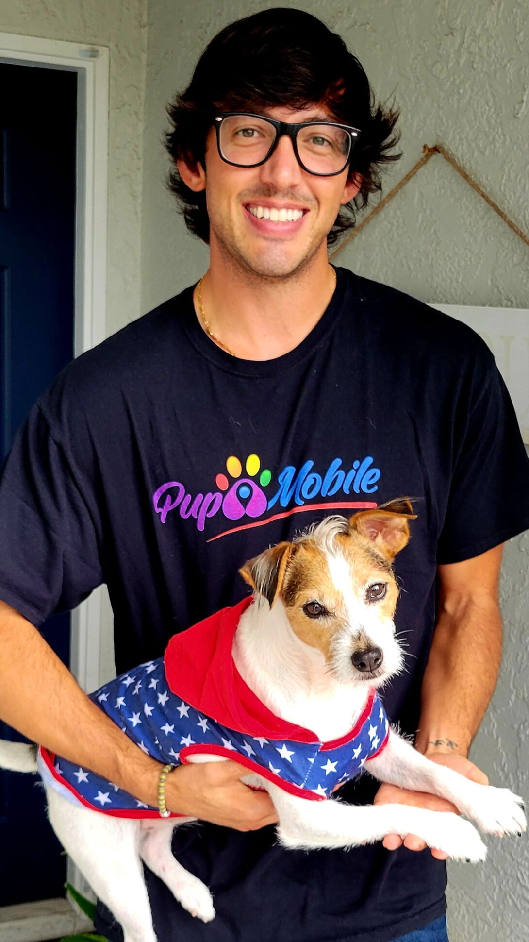 A Pup Mobile team member holding Rosie in a stars-and-stripes hoodie
